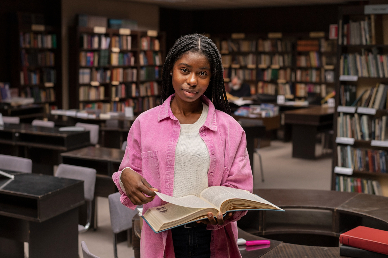 Student holding an open book in a university library